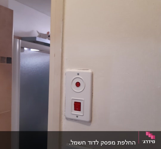 מתגי חשמל על קיר לבן עם כפתור אדום
